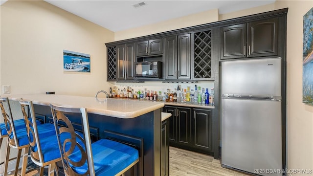 bar featuring stainless steel fridge and light wood-type flooring