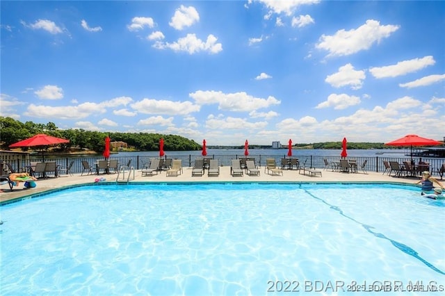 view of swimming pool with a water view and a patio area