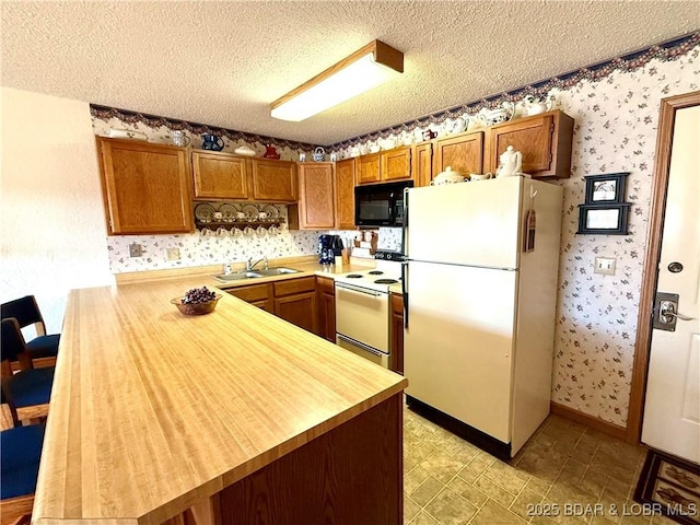 kitchen featuring white appliances, kitchen peninsula, and a textured ceiling