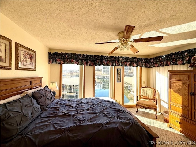 bedroom with multiple windows, access to exterior, a textured ceiling, and ceiling fan