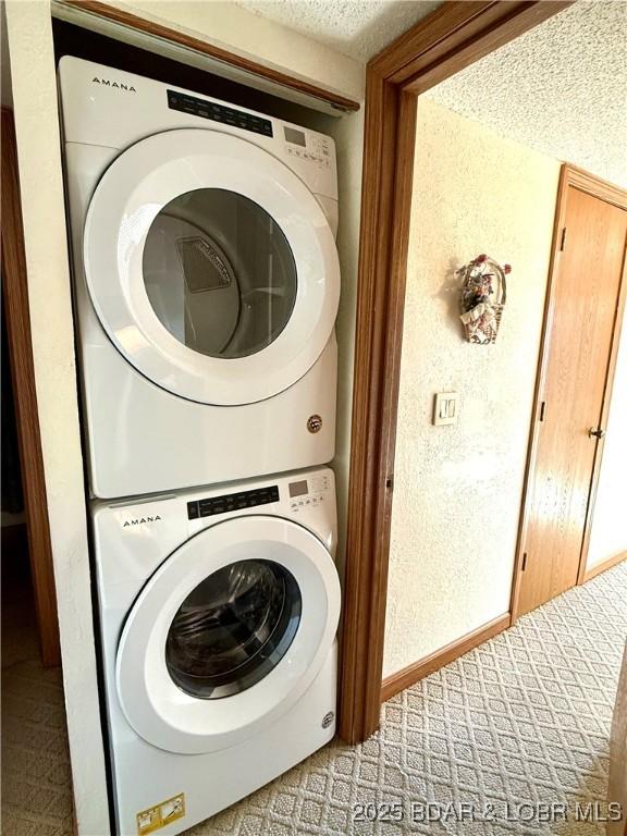 washroom with stacked washer and dryer and a textured ceiling