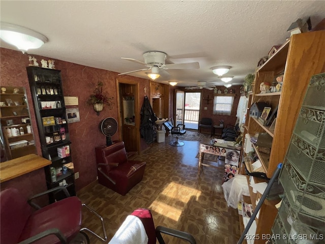 living room featuring ceiling fan and a textured ceiling