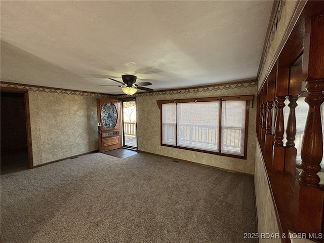 spare room with ornamental molding, ceiling fan, and dark colored carpet