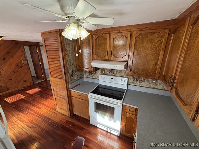 kitchen with ceiling fan, white electric stove, dark hardwood / wood-style flooring, and wood walls