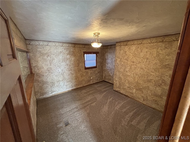 empty room featuring a textured ceiling and dark colored carpet