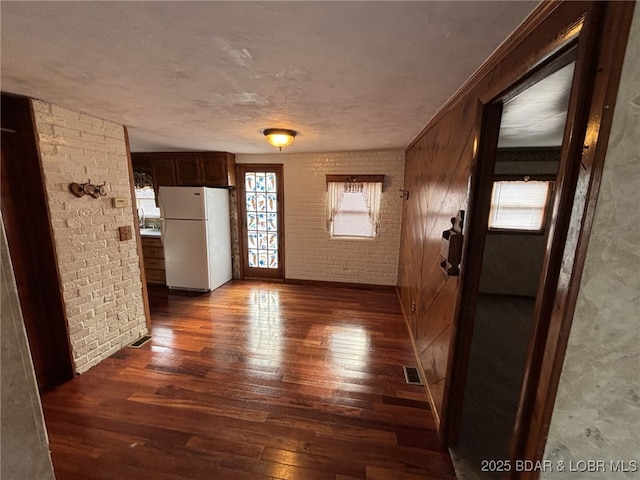 interior space with brick wall, dark hardwood / wood-style floors, and sink