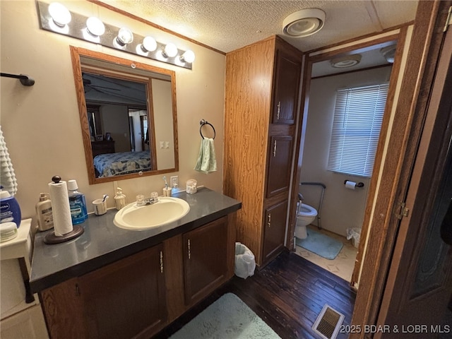 bathroom with vanity, hardwood / wood-style flooring, toilet, and a textured ceiling