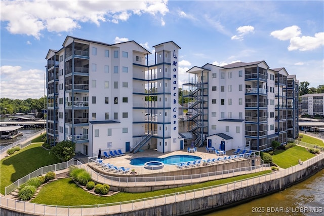 view of building exterior featuring a water view and a community pool