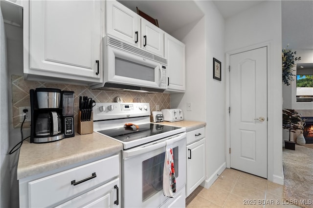 kitchen with white appliances, decorative backsplash, and white cabinets