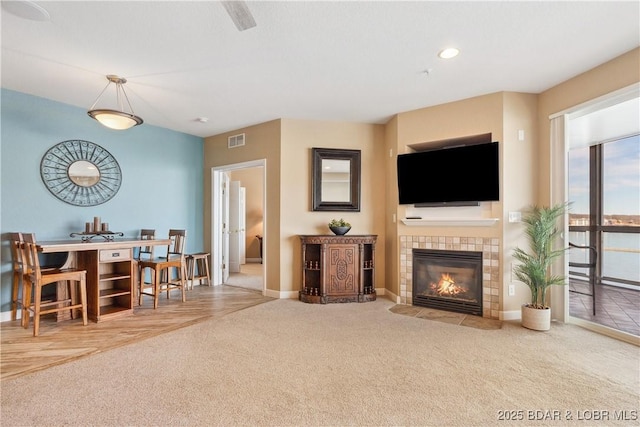 carpeted living room featuring a tiled fireplace