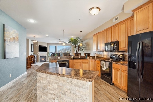 kitchen featuring light hardwood / wood-style flooring, hanging light fixtures, kitchen peninsula, decorative backsplash, and black appliances