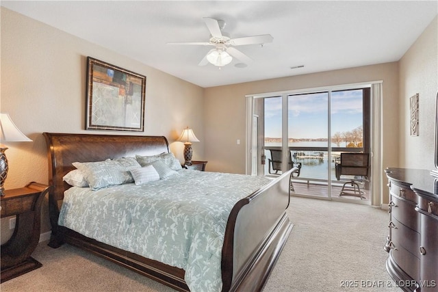 bedroom featuring a water view, ceiling fan, light carpet, and access to outside