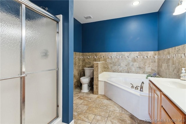 full bathroom featuring vanity, separate shower and tub, tile walls, and toilet