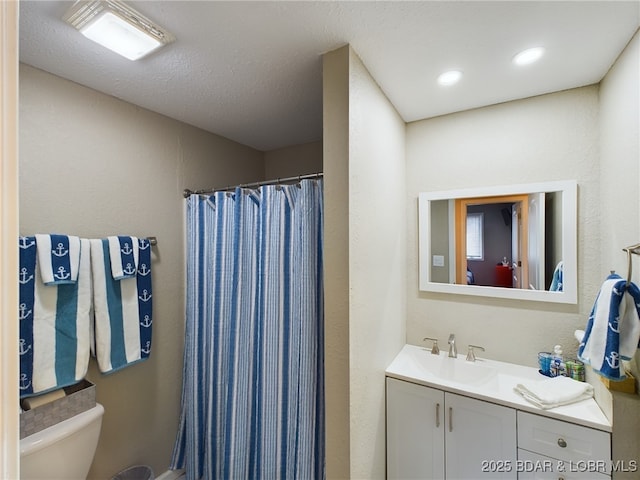 bathroom featuring walk in shower, vanity, and toilet