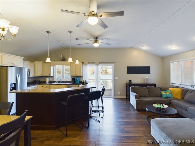 kitchen with lofted ceiling, stainless steel fridge, dark hardwood / wood-style flooring, and a breakfast bar area