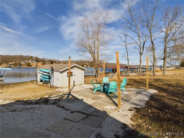 view of yard featuring a water view, a patio area, and a shed