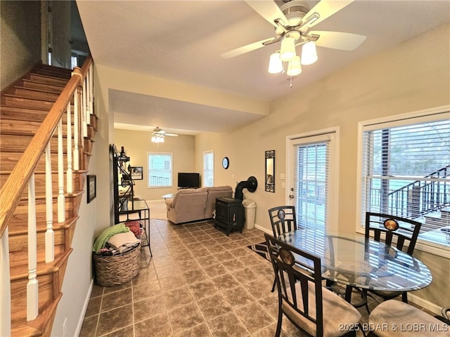 dining room featuring ceiling fan and a wood stove