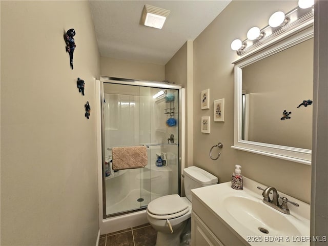 bathroom with tile patterned floors, vanity, toilet, and a shower with door