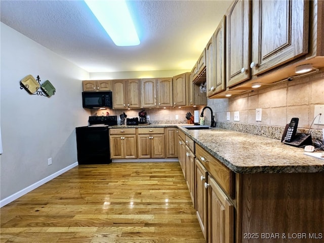 kitchen featuring tasteful backsplash, sink, light hardwood / wood-style floors, black appliances, and a textured ceiling