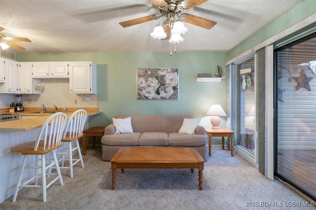 living room featuring sink, light colored carpet, a textured ceiling, and ceiling fan