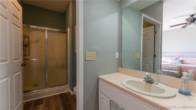 bathroom with ceiling fan, hardwood / wood-style floors, an enclosed shower, vanity, and toilet