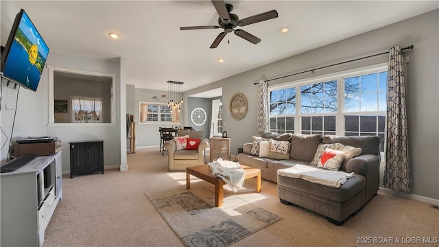 carpeted living room featuring ceiling fan with notable chandelier