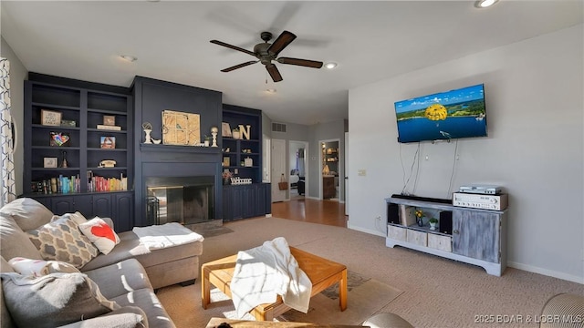 carpeted living room featuring built in shelves and ceiling fan