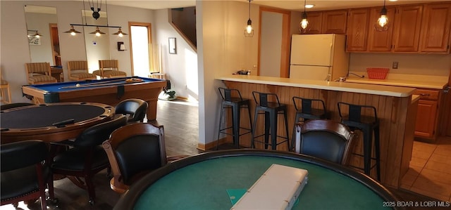 bar with white refrigerator, hanging light fixtures, dark tile patterned floors, and billiards