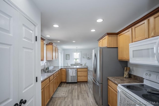 kitchen featuring appliances with stainless steel finishes, pendant lighting, sink, kitchen peninsula, and light wood-type flooring