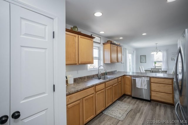 kitchen with sink, stainless steel appliances, a wealth of natural light, decorative light fixtures, and kitchen peninsula