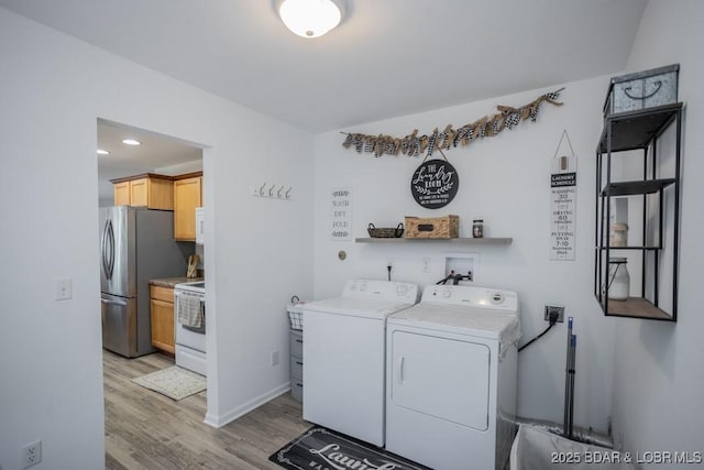 clothes washing area featuring washer and dryer and light wood-type flooring