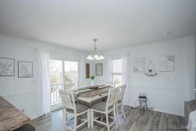 dining space with a notable chandelier and light hardwood / wood-style floors