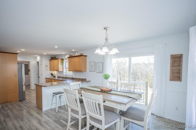 dining space featuring sink, a chandelier, and light wood-type flooring