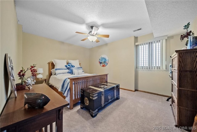 bedroom with a textured ceiling, light colored carpet, and ceiling fan