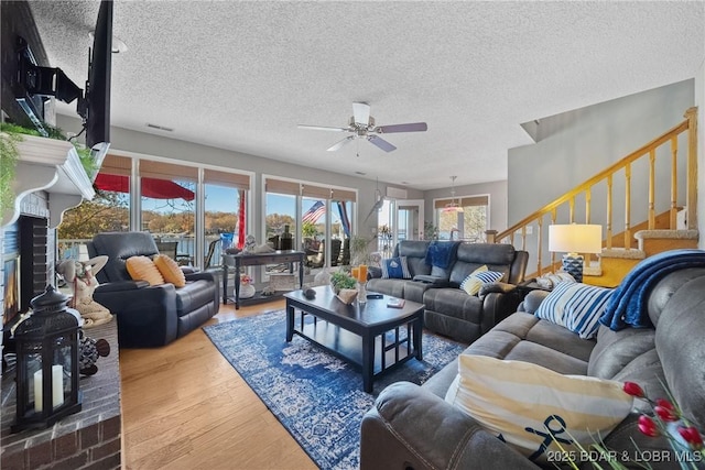 living room featuring ceiling fan, wood-type flooring, and a textured ceiling