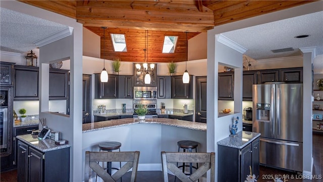 kitchen featuring a kitchen bar, light stone counters, stainless steel appliances, crown molding, and a textured ceiling