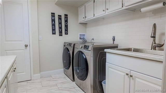 laundry room with independent washer and dryer, cabinets, and sink