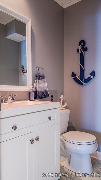 bathroom with ornamental molding, vanity, and toilet