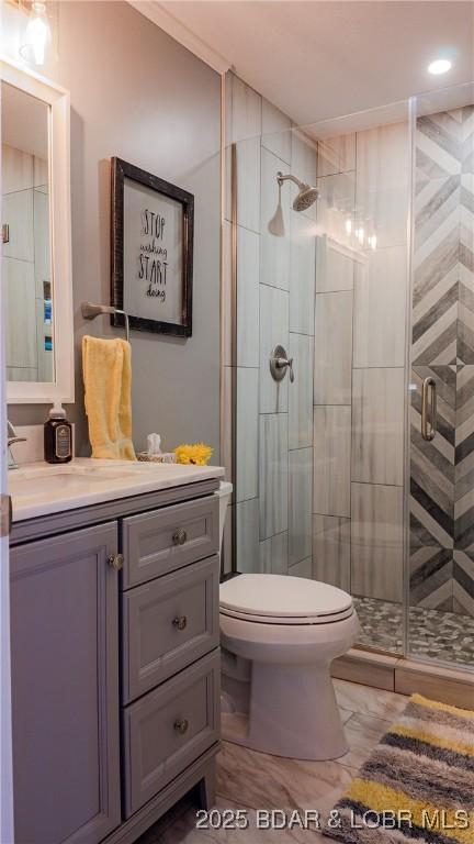 bathroom with a shower with door, vanity, and toilet