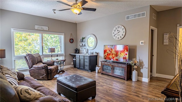 living room featuring hardwood / wood-style flooring, ceiling fan, and a textured ceiling