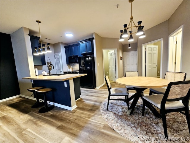 kitchen featuring blue cabinetry, a breakfast bar, sink, kitchen peninsula, and black appliances