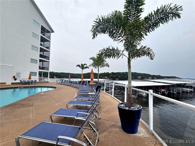 view of pool featuring a water view and a patio area