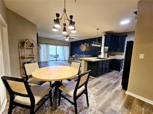 dining area with hardwood / wood-style flooring, sink, and ceiling fan with notable chandelier