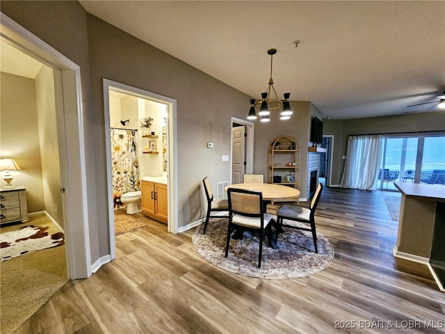 dining area featuring ceiling fan with notable chandelier and light hardwood / wood-style floors