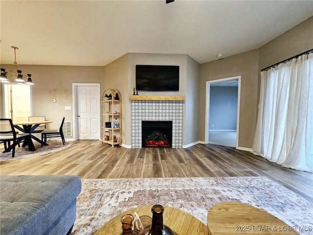 living room with a tiled fireplace and hardwood / wood-style floors