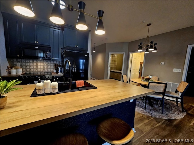 kitchen with pendant lighting, butcher block countertops, dark hardwood / wood-style floors, black appliances, and blue cabinets