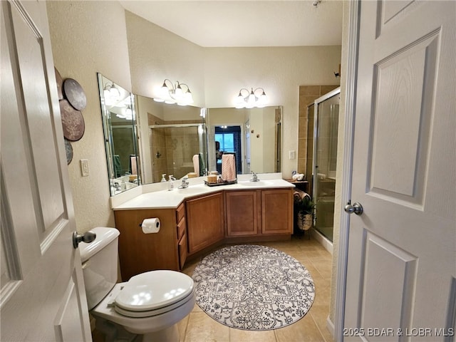 full bathroom with double vanity, a textured wall, tile patterned floors, a sink, and a stall shower