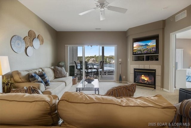 carpeted living room with a fireplace and ceiling fan