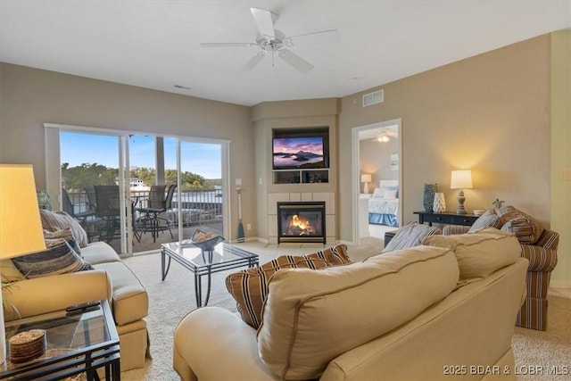 living room with light colored carpet, a tile fireplace, and ceiling fan