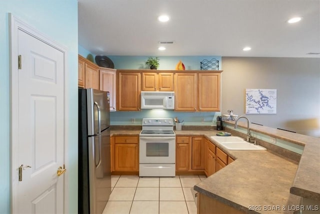 kitchen with sink, white appliances, light tile patterned floors, and kitchen peninsula